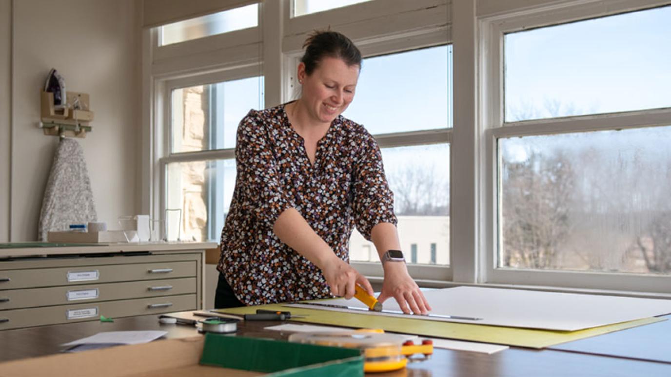 Museum staff trimming an item for display in the gallery