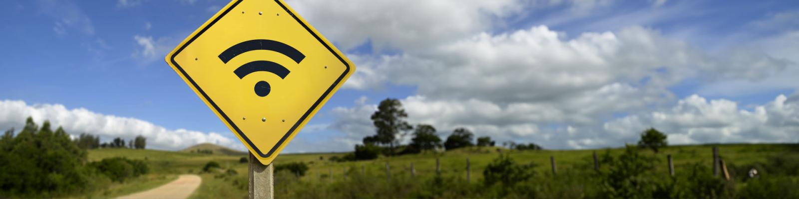 Yellow Road sign depicting a wifi symbol with rural fields in the background