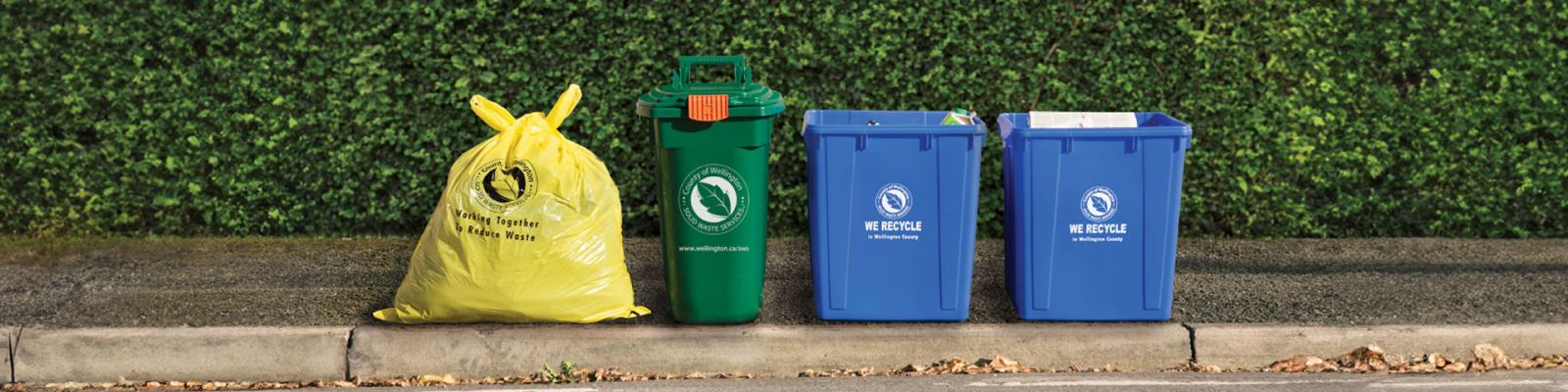 Garbage bag, green bin and recycling boxes set curbside for pick up