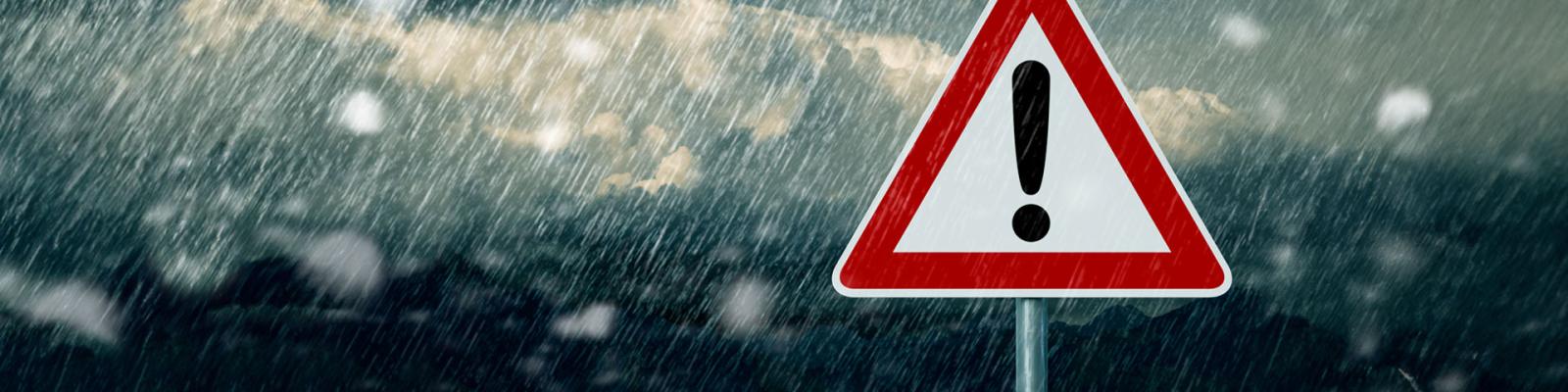 Caution road sign amidst a dark, stormy background