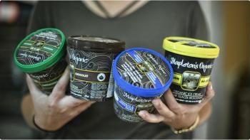 A woman holds four pints of Mapleton's ice cream in her hands, all with different colour tops. 