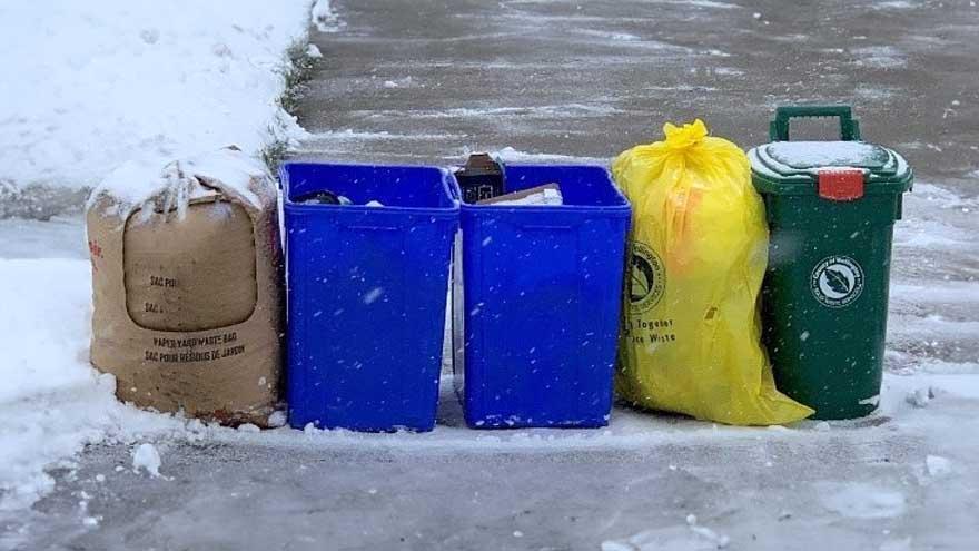 Curbside Collection set out in the Winter with a yard bag, two blue boxes a yellow garbage bag and green bin all in a row at the end of a driveway
