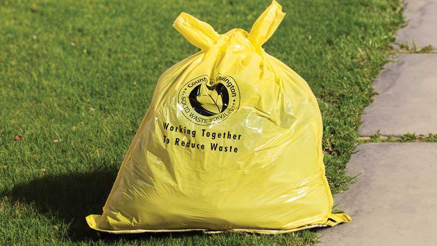 Yellow user pay garbage bag filled with garbage